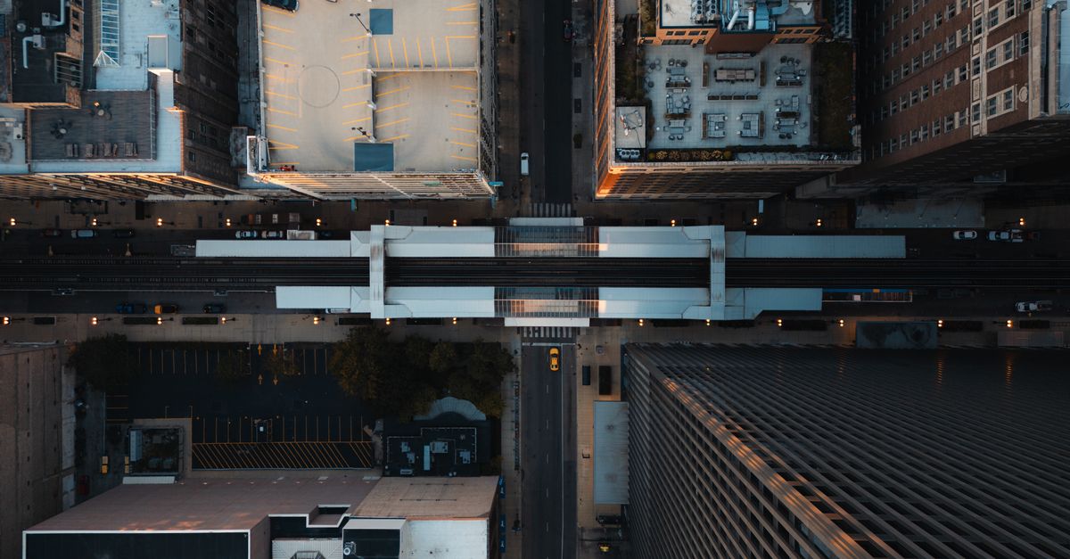 Aerial city view showcasing tall buildings, train tracks, and streets forming a grid layout.